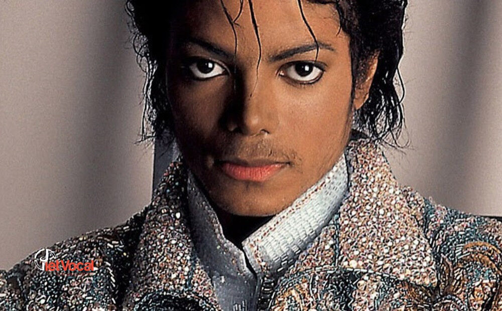 alt text: Michael Jackson trong trang phục biểu diễn đặc trưng, mũ phớt và áo khoác da, đang thực hiện một trong những bước nhảy nổi tiếng của mình.