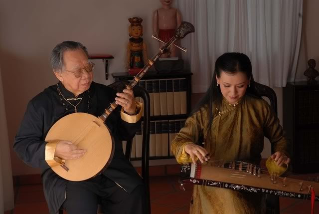 alt text:  Một nghệ sĩ đang chơi đàn nguyệt, thể hiện cách cầm móng gảy và bấm dây đàn.